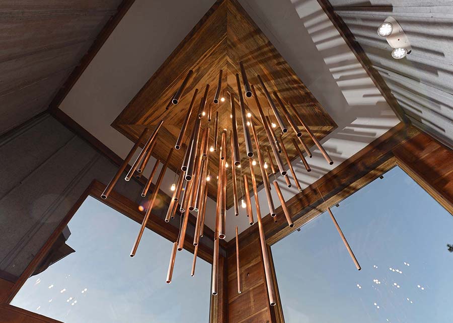Looking up into the copper tubing of the pendant, iridescent bulbs can be seen through them